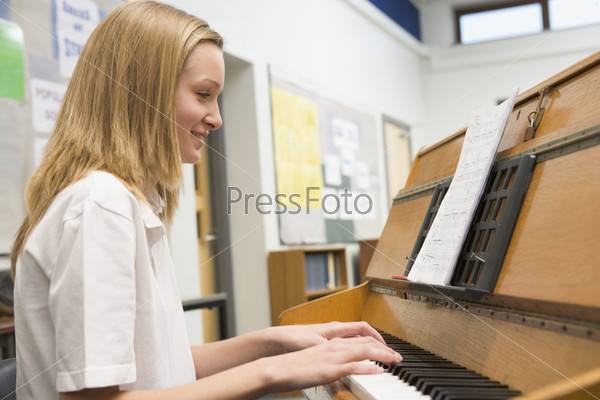 Молодая девушка за фортепиано в музыкальном классе