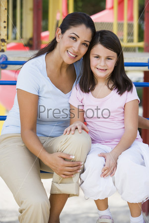 Mother and daughter in playground on climbing frame
