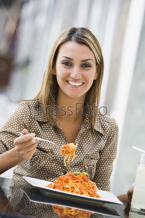 Woman eating pasta at cafe