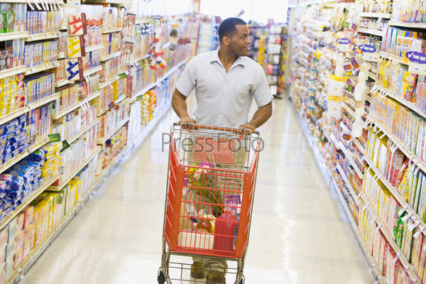 Man pushing trolley along supermarket grocery aisle