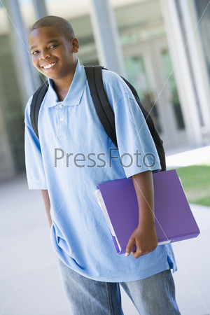 Elementary school pupil outside carrying folder