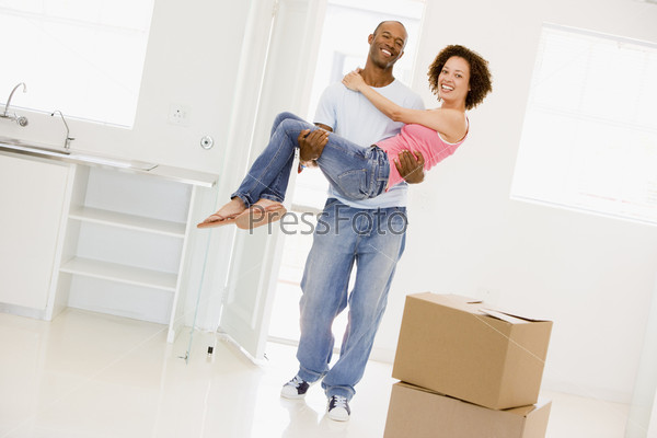 Husband holding wife in new home smiling