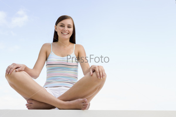oman sitting cross legged outside against blue sky