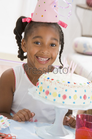 Девочка задувает свечи на торте в свой день рождения