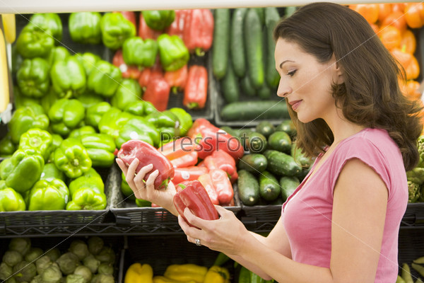 Женщина выбирает овощи в супермаркете