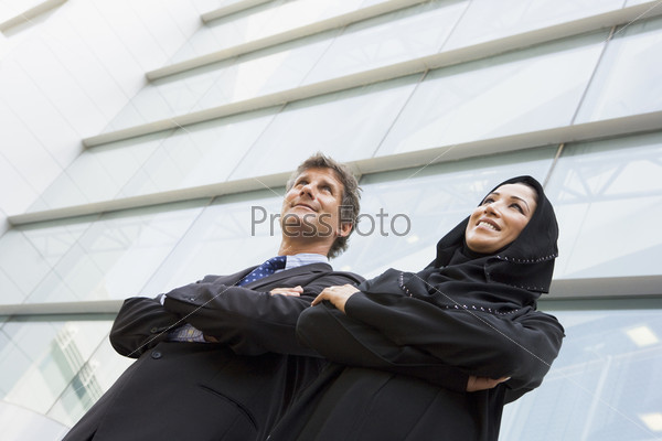 A Middle Eastern businesswoman and a CSaucasian man standing out
