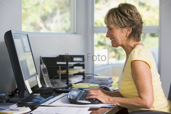 Пожилая женщина европейской национальности, работающая за домашним компьютером