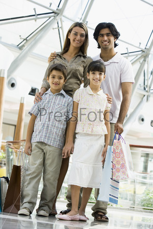 Family shopping in mall carrying bags