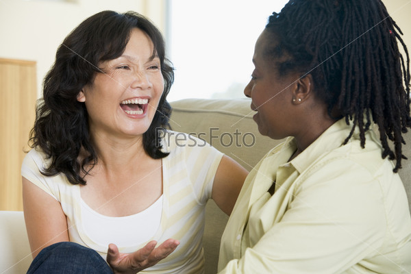 Two women talking in living room and smiling