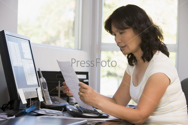 Woman in home office with computer and paperwork