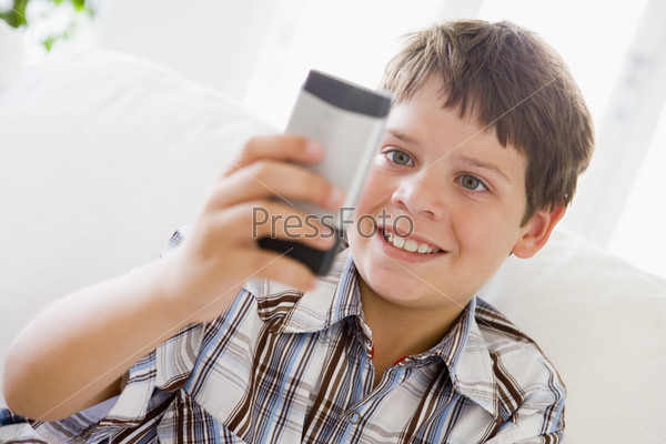 Young Boy Sitting On A Sofa Texting On A Mobile Phone
