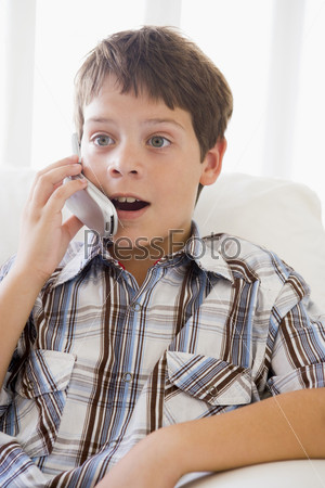 Young Boy Sitting On A Sofa Talking On A Mobile Phone
