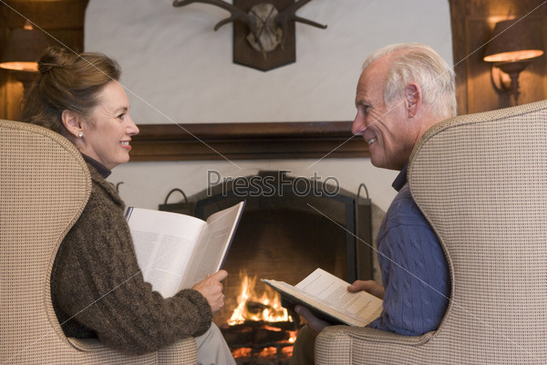 Couple sitting in living room by fireplace with books smiling