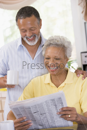 Мужчина и женщина смеются, читая газету
