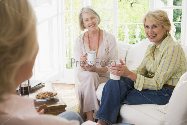 Three women in living room with coffee smiling