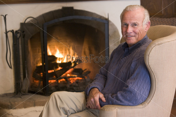 Man sitting in living room by fireplace smiling