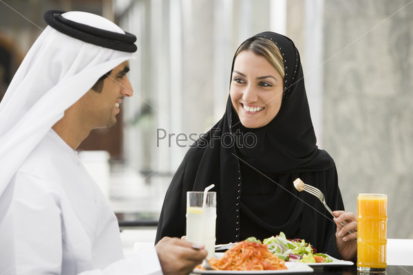Couple at restaurant eating and smiling (selective focus)