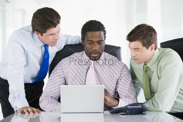 Три бизнесмена в зале заседаний с ноутбуком