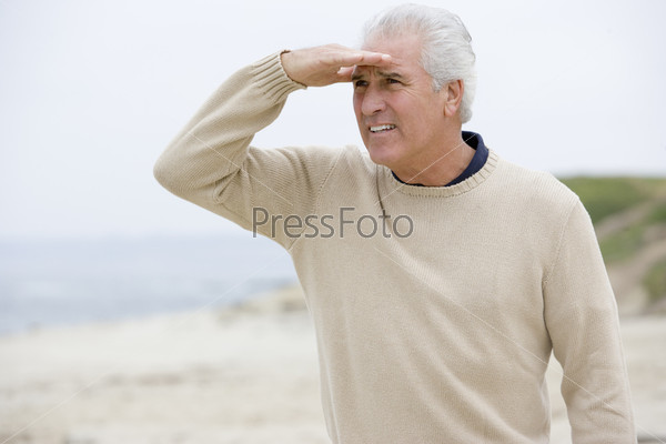 Man at the beach looking out with hand over eyes