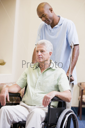 Медбрат везет пожилого мужчину в инвалидном кресле