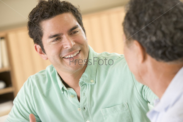 Two men sitting in living room talking and smiling