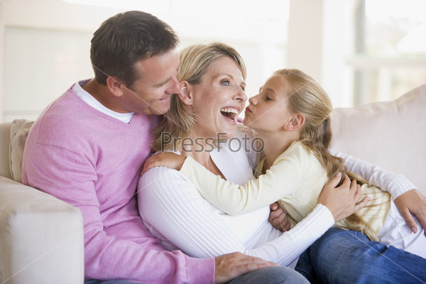 Family in living room with young girl kissing woman