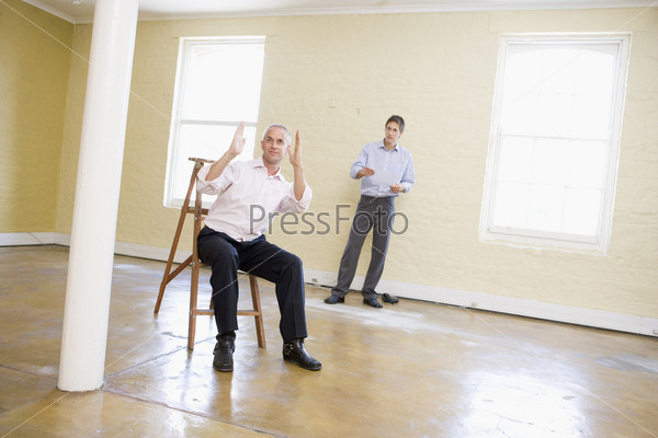 Two men with ladder in empty space making plans for room