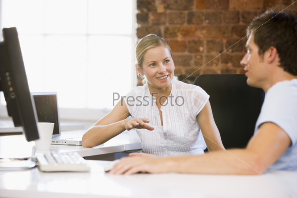 Two businesspeople in office talking and smiling