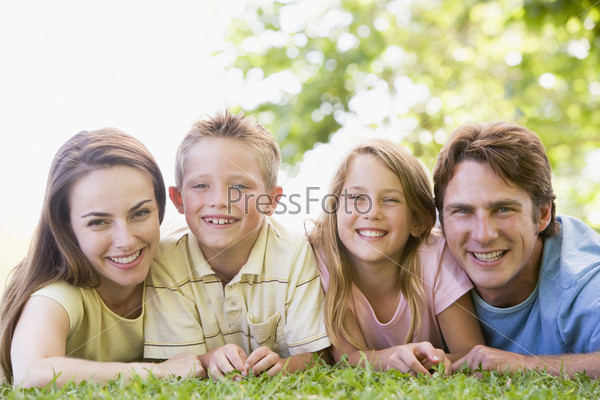 Family lying outdoors smiling
