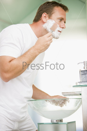 Мужчина бреется в ванной
