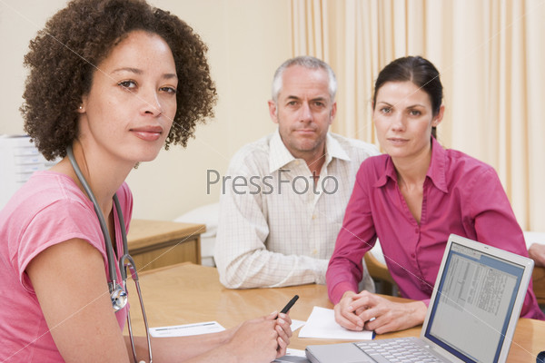 Doctor with laptop and couple in doctor\'s office