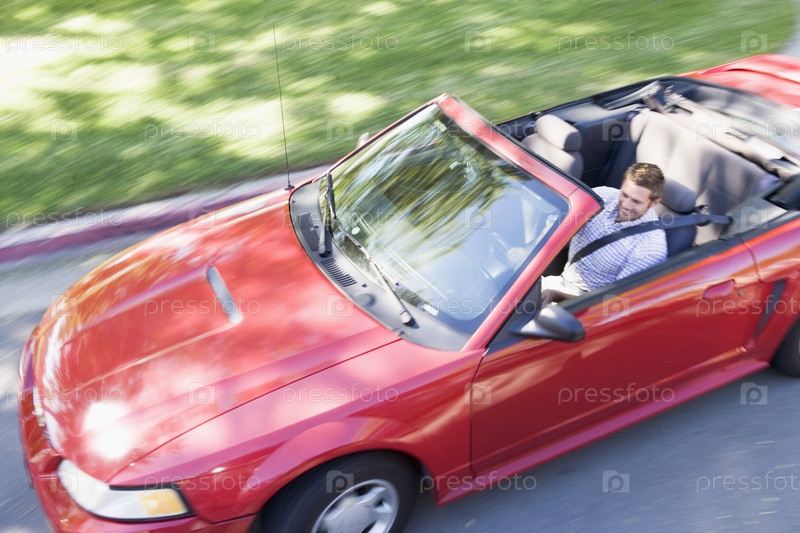 Man driving convertible car smiling