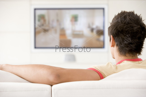 Молодой человек смотрит телевизор в гостиной