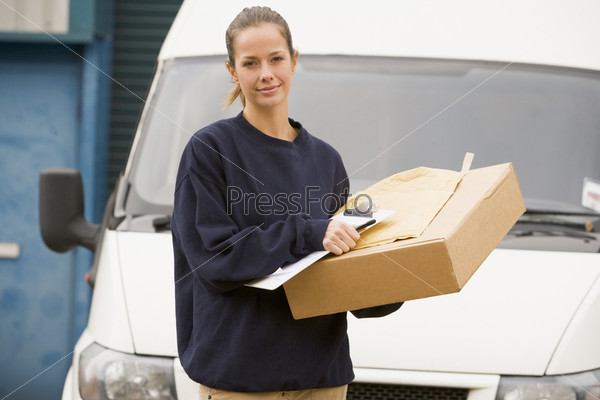Девушка-курьер с коробкой и документами на фоне фургона