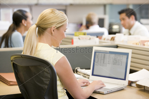 Businesswoman in cubicle using laptop