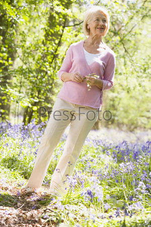 Woman standing outdoors holding flower smiling