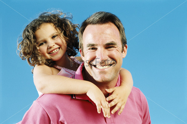 Father giving daughter piggyback ride outdoors smiling