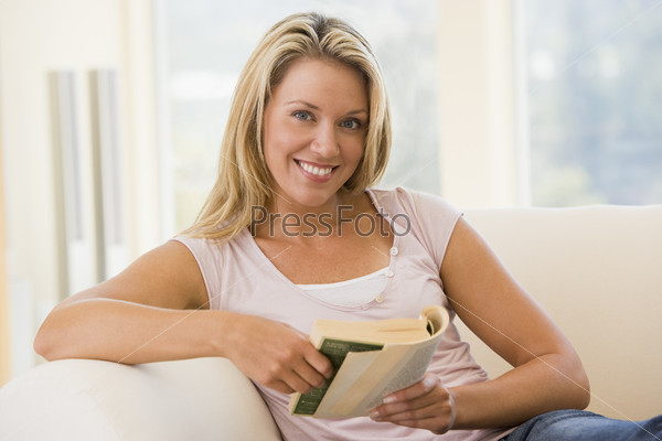Woman in living room reading book smiling