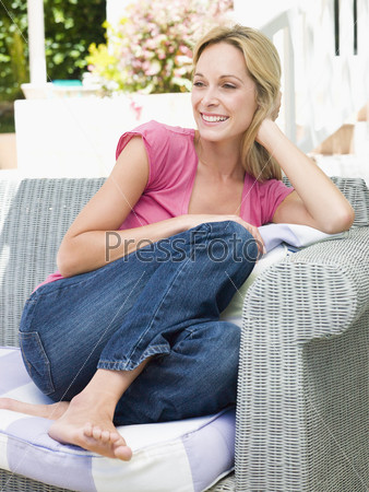 Woman sitting outdoors on patio smiling