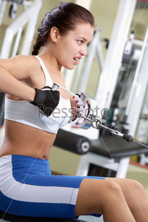 Photo of active girl pumping muscles on special equipment