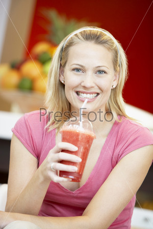 Молодая женщина пьет коктейль в кафе