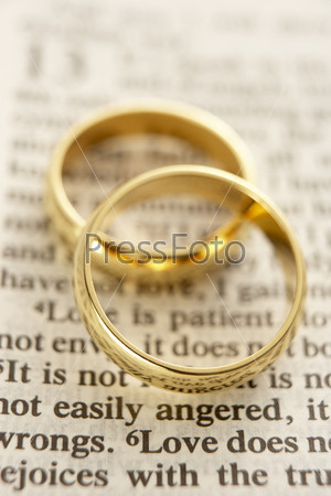 Two Wedding Rings Resting On A  Bible Page