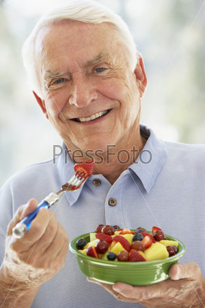 Пожилой мужчина ест фруктовый салат