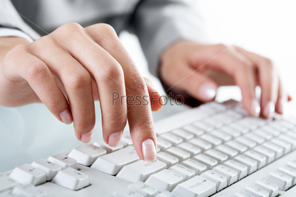 Macro image of human hand with forefinger going to press key on keyboard