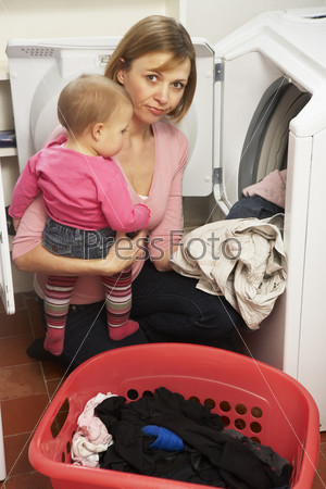 Woman Doing Laundry And Holding Baby Daughter