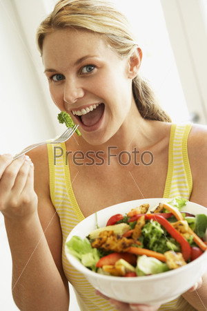 Молодая женщина ест салат