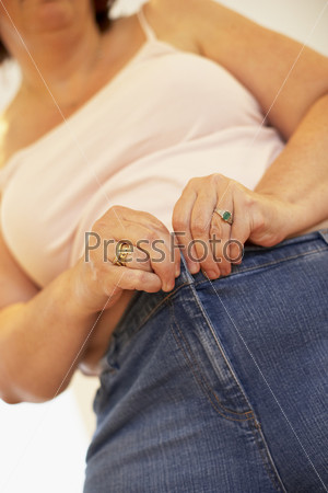 Полная женщина пытается застегнуть джинсы