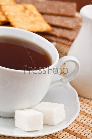 A cup of black tea with a lump sugar and crackers for breakfast