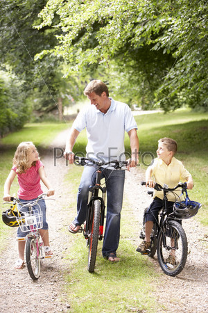 Father and children riding bikes in countryside