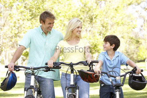 Мама, папа и сын катаются на велосипедах по парку